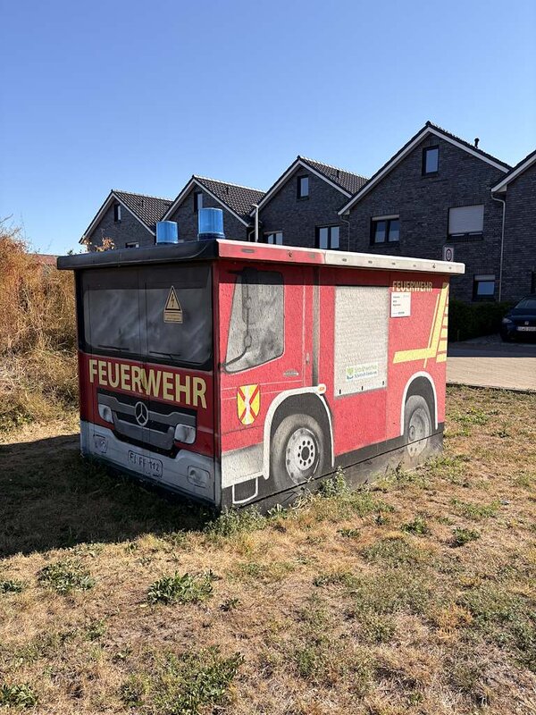 Ein kleines Trafohäuschen, dass mit Grafitti wie ein Feuerwehrauto angemalt wurde.