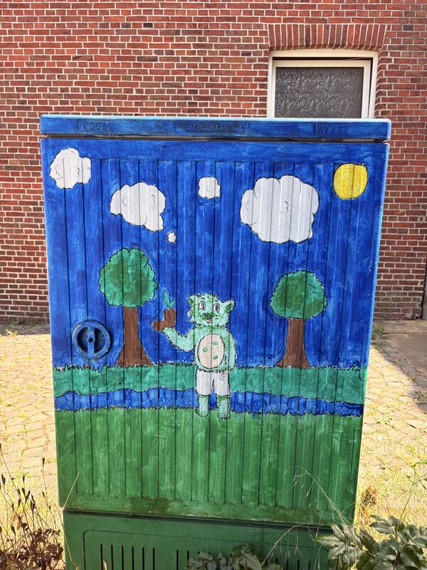 Ein Stromkasten, der mit Grafitti bemalt wurde und wo eine Landschaft mit einem Grünen Bär zu sehen ist.