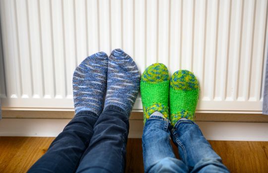 Blaue und grüne Socken lehnen an einer Heizung