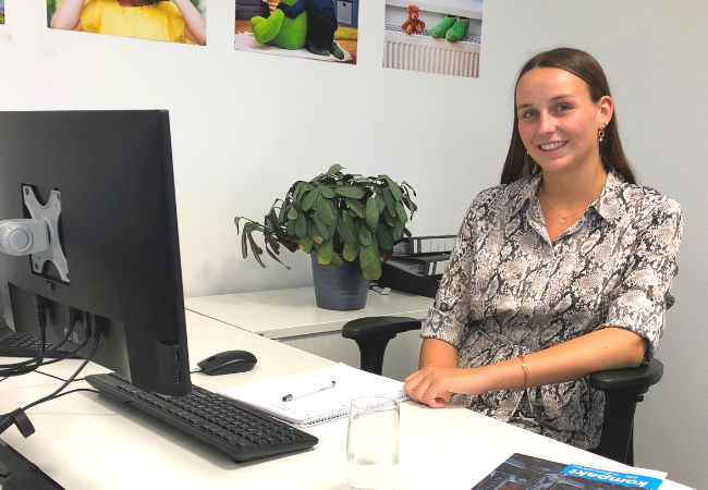 Mädchen mit gemusterter Bluse sitzt am Schreibtisch