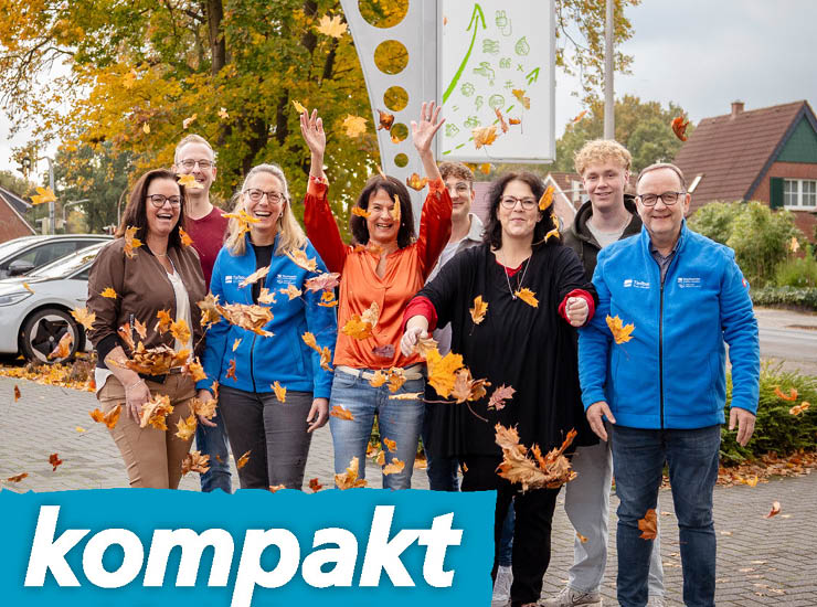 Personen stehen zusammen und werfen Blätter hoch