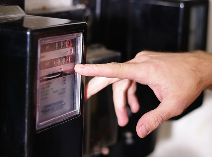 Hand zeigt mit Zeigefinger auf Stromzähler