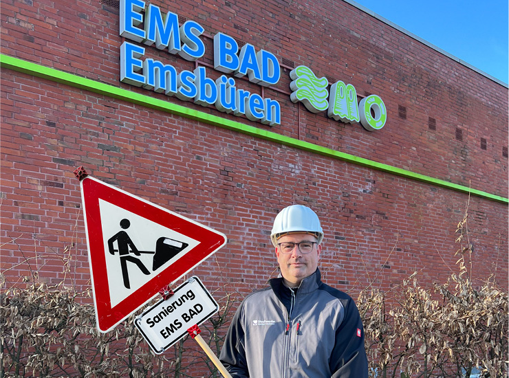 Mann steht vor EMS BAD und hält Baustellenschild in der Hand