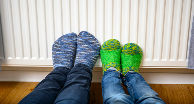 Kinderfüße mit bunten Socken lehnen an der Heizung