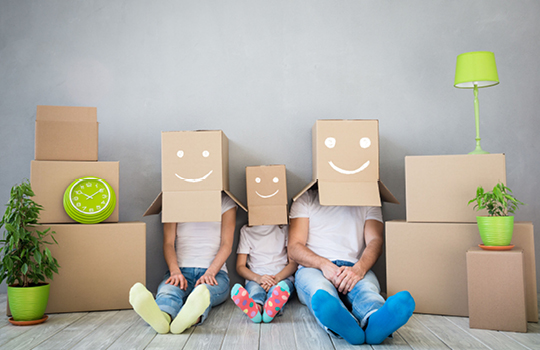 Junge Familie mit Kartons auf dem Kopf und Smileys